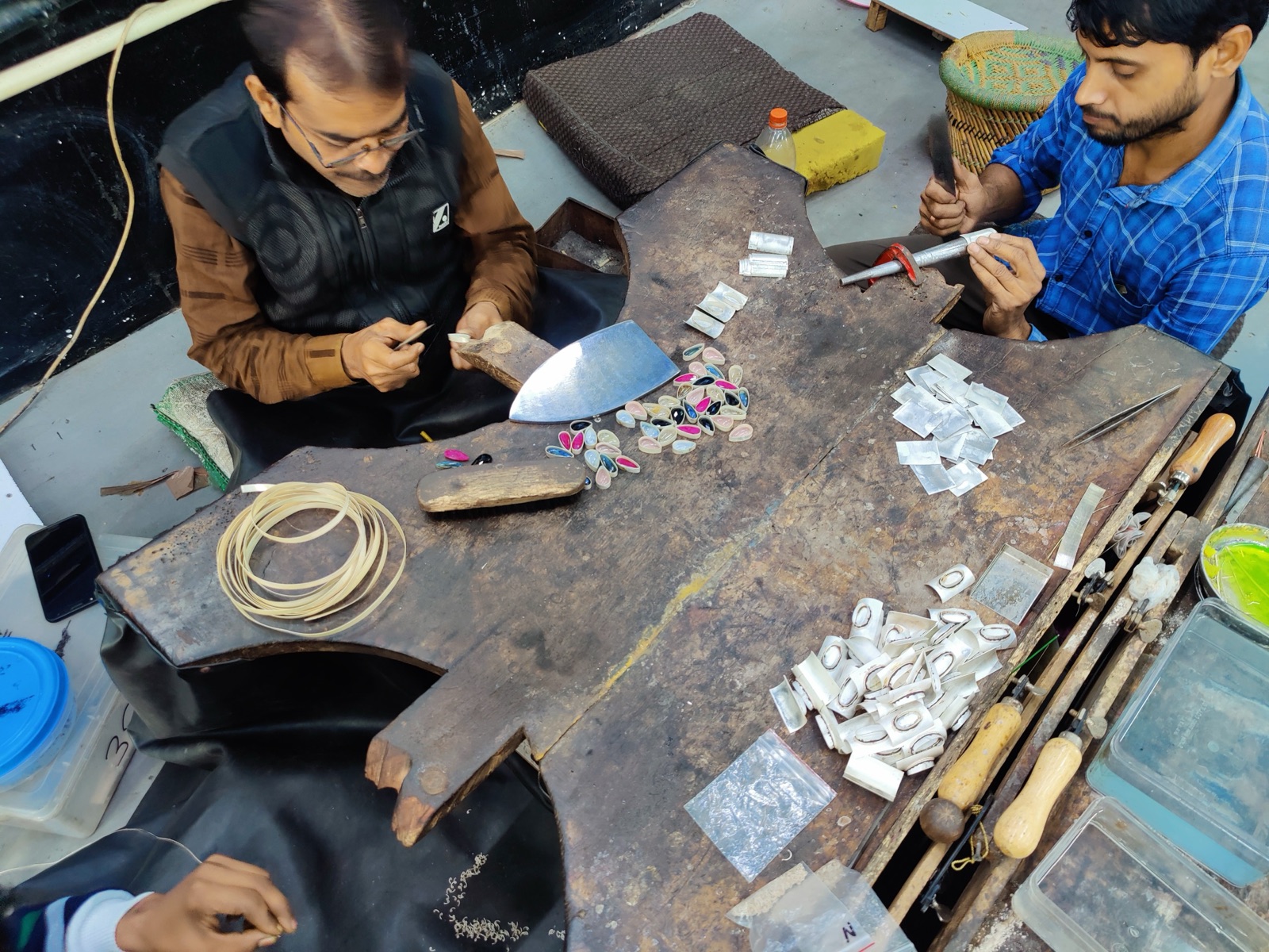 Craftsmen setting natural gemstones into 925 silver bezels by hand